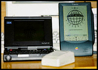 Photograph of the IBM PC110, lid open, standing beside an Apple Newton